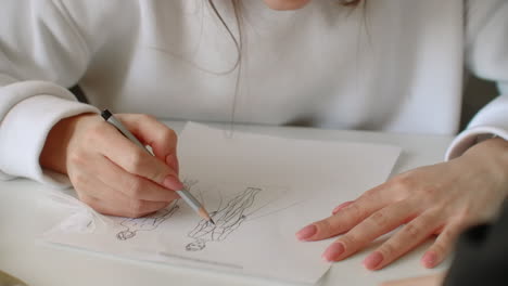 Cerca-De-Dos-Mujeres-Jóvenes-Que-Trabajan-Como-Diseñadoras-De-Moda-Y-Dibujan-Bocetos-Para-Ropa-En-El-Taller.